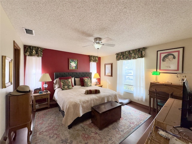 bedroom with a textured ceiling, ceiling fan, and hardwood / wood-style floors