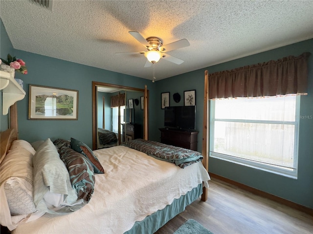 bedroom with ceiling fan, a closet, light wood-type flooring, and a textured ceiling