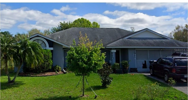 view of front of home with a garage, a shingled roof, and a front yard