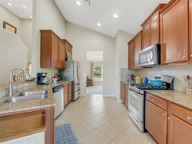 kitchen with sink, light tile patterned floors, stainless steel appliances, light stone countertops, and decorative backsplash