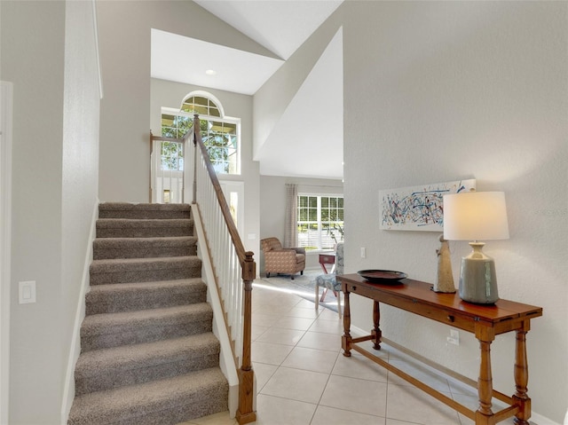 staircase featuring tile patterned flooring, a wealth of natural light, and high vaulted ceiling