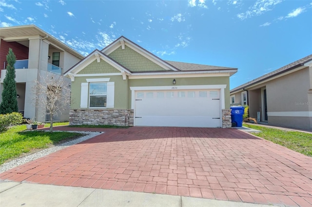 craftsman house featuring stone siding, decorative driveway, an attached garage, and stucco siding