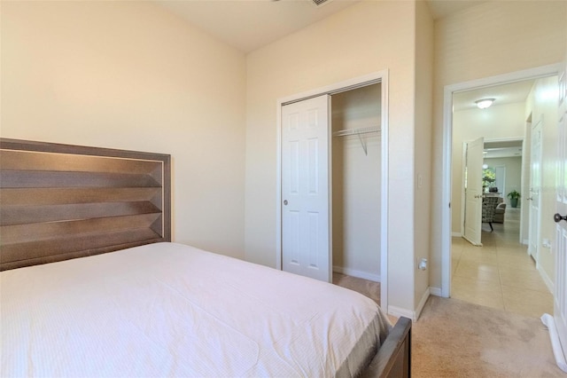 bedroom with light tile patterned flooring, baseboards, a closet, and light colored carpet