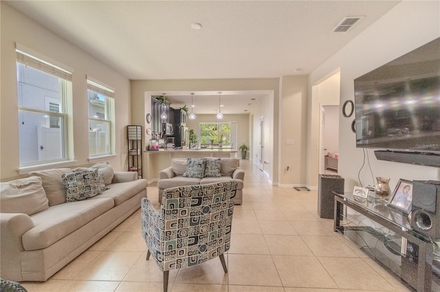 living area with light tile patterned flooring, visible vents, and baseboards