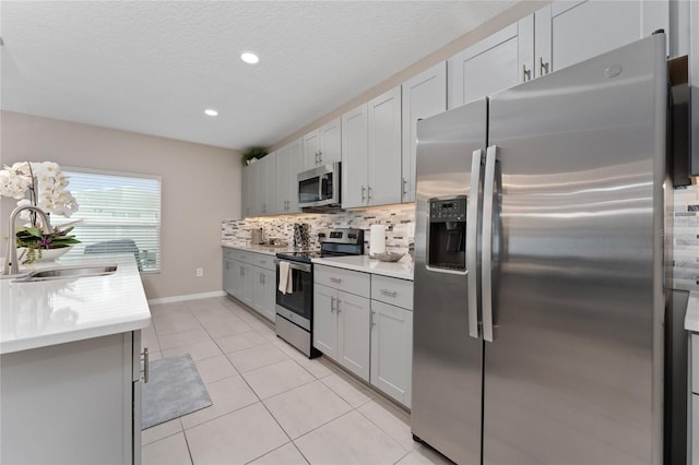 kitchen featuring tasteful backsplash, sink, light tile patterned flooring, gray cabinetry, and stainless steel appliances