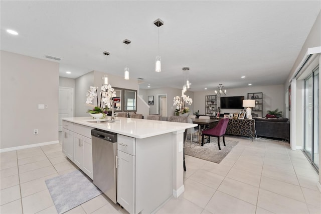 kitchen featuring a notable chandelier, pendant lighting, stainless steel dishwasher, a kitchen island with sink, and white cabinets