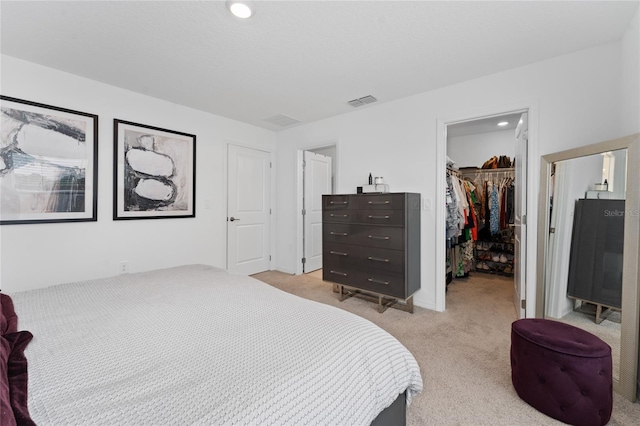 bedroom with light carpet, a walk in closet, and a closet