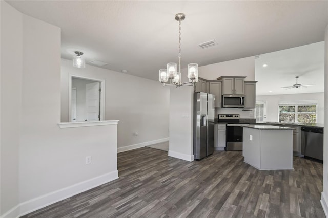 kitchen featuring appliances with stainless steel finishes, gray cabinetry, hanging light fixtures, dark hardwood / wood-style floors, and a kitchen island