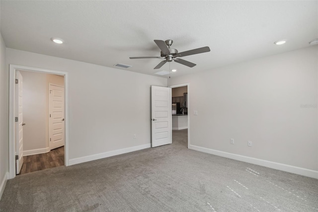 unfurnished bedroom featuring dark carpet and ceiling fan