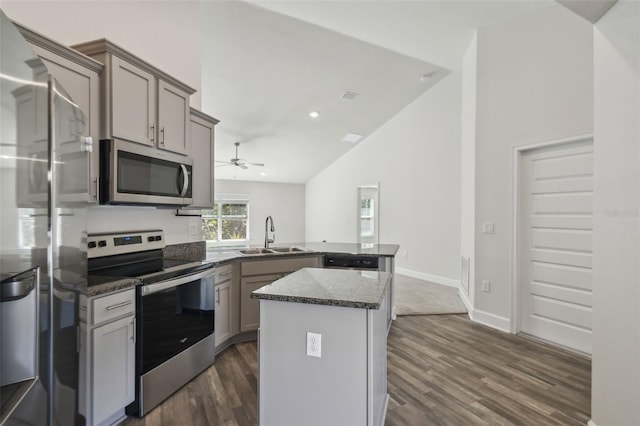 kitchen with sink, vaulted ceiling, appliances with stainless steel finishes, kitchen peninsula, and a kitchen island