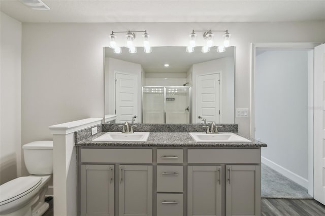 bathroom with wood-type flooring, vanity, an enclosed shower, and toilet