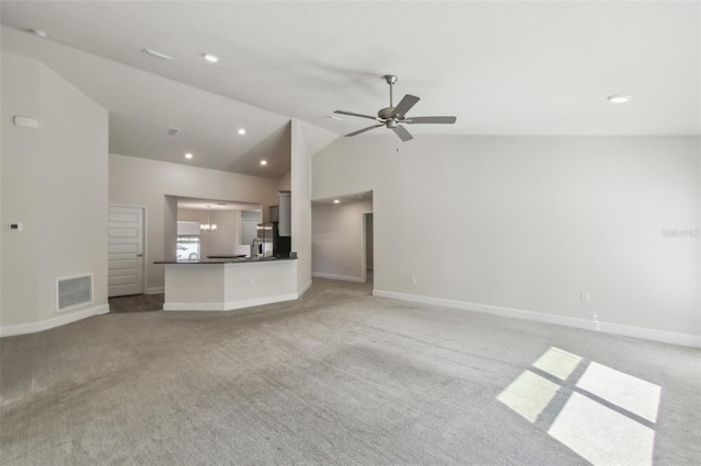 unfurnished living room with lofted ceiling, ceiling fan with notable chandelier, and light carpet