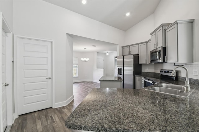 kitchen featuring appliances with stainless steel finishes, sink, dark hardwood / wood-style floors, and decorative light fixtures