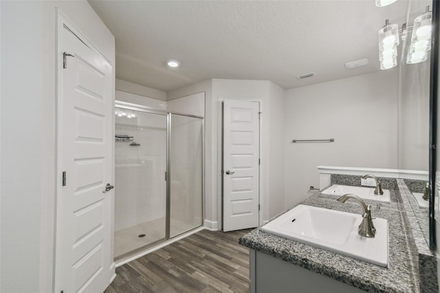 bathroom with vanity, hardwood / wood-style floors, and a shower with door