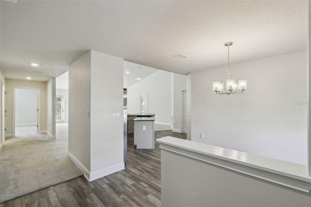 kitchen with dark wood-type flooring, decorative light fixtures, and an inviting chandelier