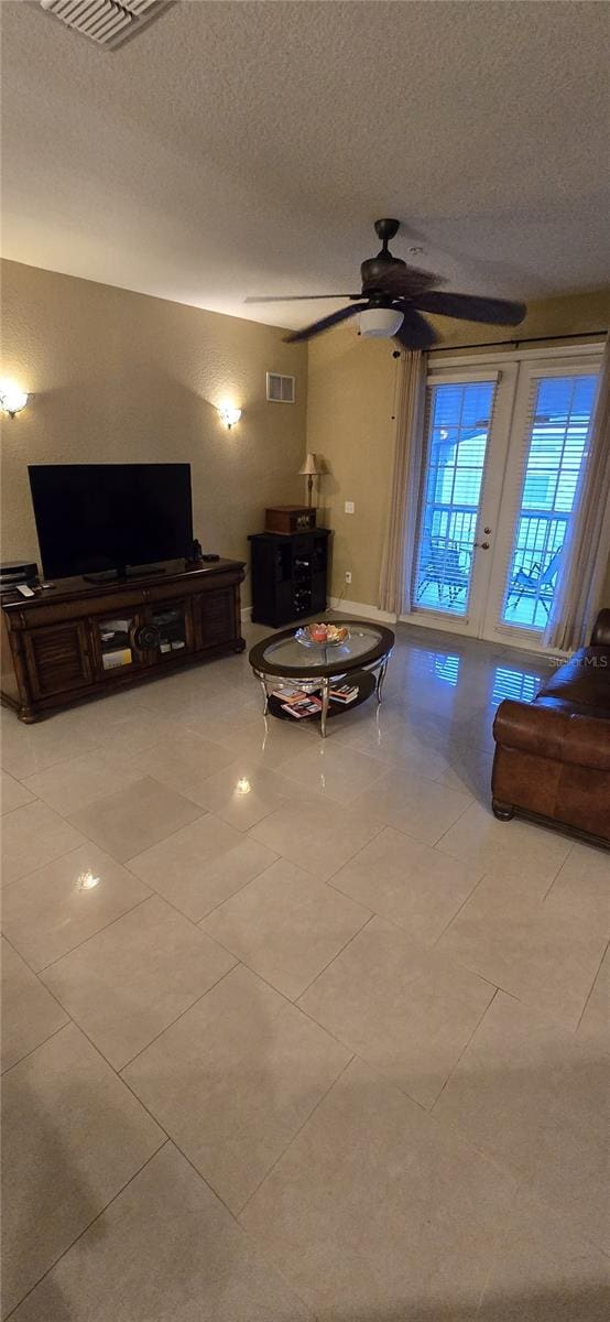 unfurnished living room with a textured ceiling, ceiling fan, and french doors