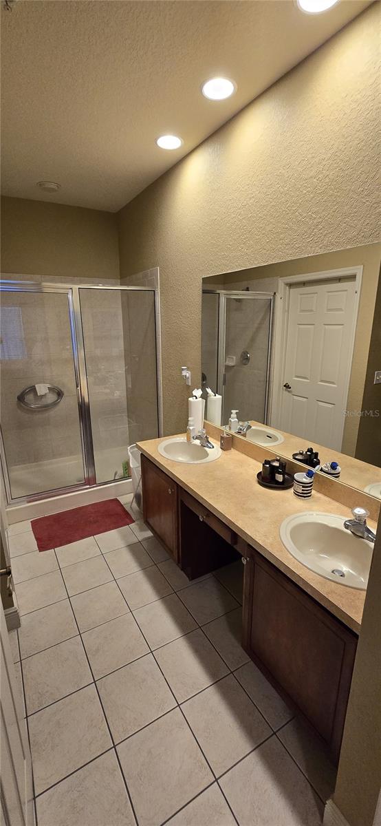 bathroom featuring walk in shower, vanity, tile patterned floors, and a textured ceiling