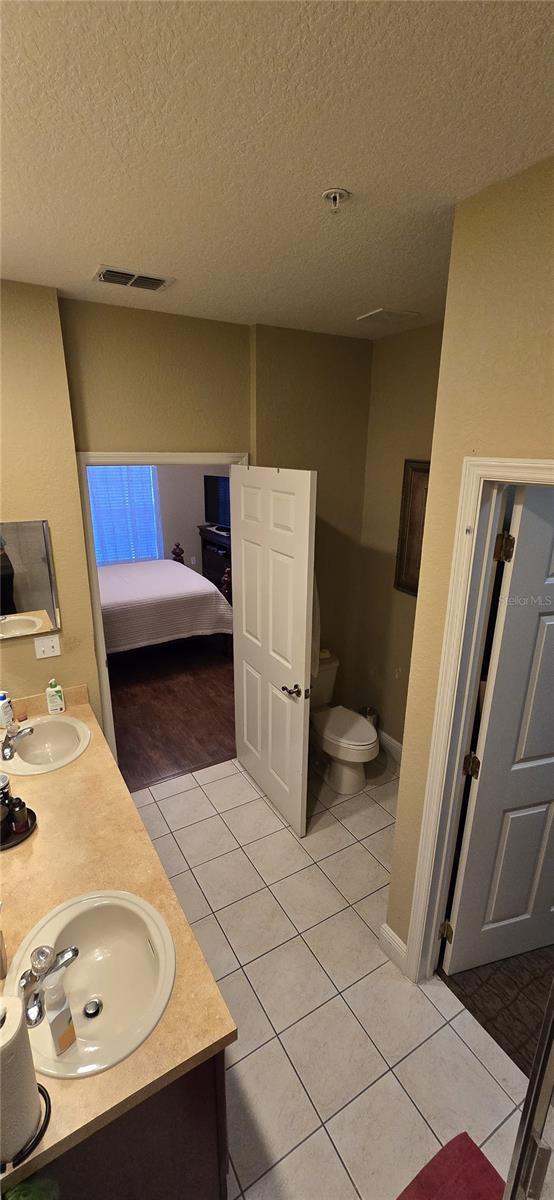 bathroom featuring a textured ceiling, toilet, tile patterned floors, and vanity