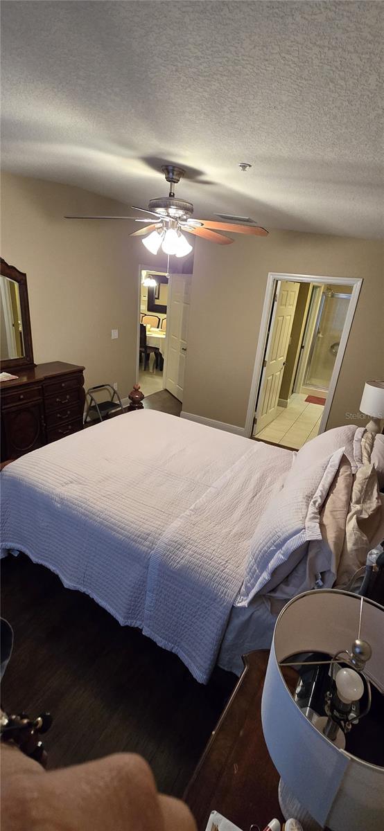 bedroom with ceiling fan, a textured ceiling, and hardwood / wood-style flooring