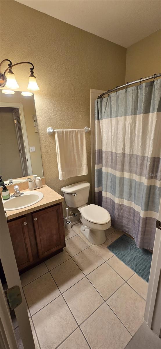 bathroom with tile patterned floors, toilet, vanity, and a shower with curtain