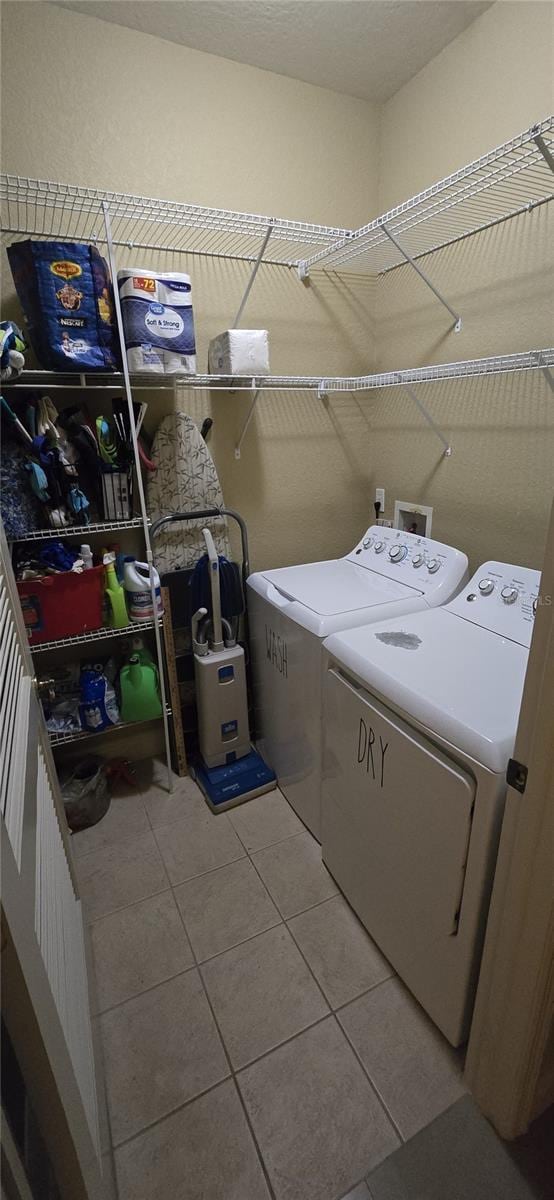 clothes washing area with light tile patterned flooring and separate washer and dryer