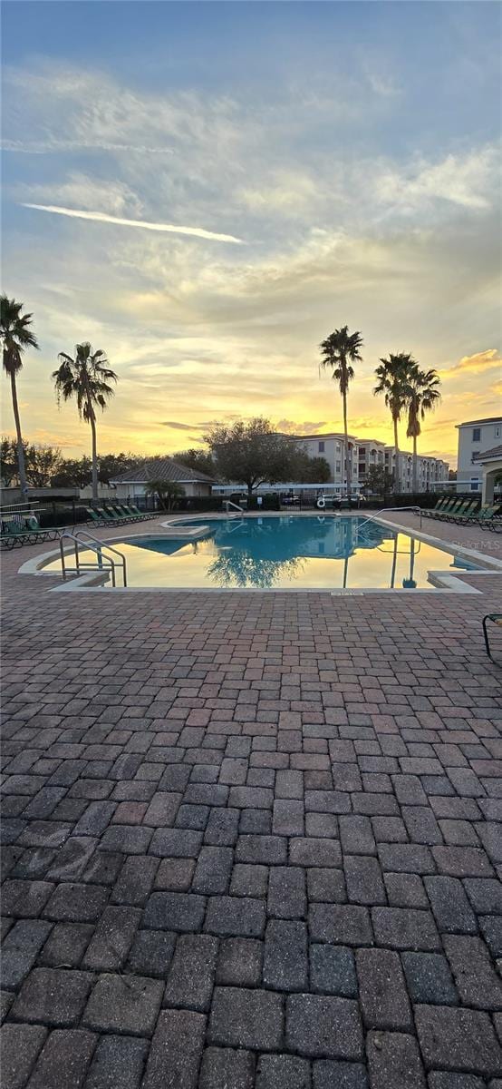 pool at dusk with a patio area