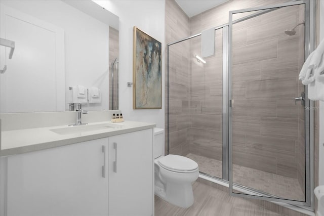 bathroom with toilet, vanity, and an enclosed shower