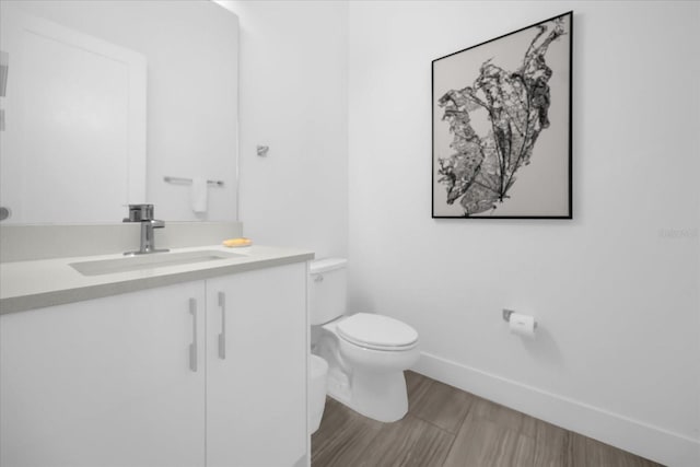 bathroom featuring wood-type flooring, toilet, and vanity