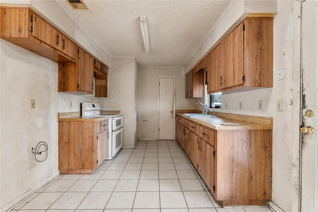 kitchen featuring sink, range with two ovens, and a textured ceiling