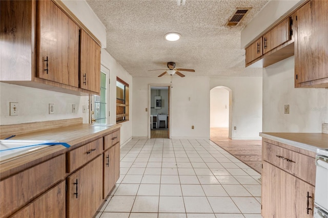 kitchen featuring ceiling fan, a textured ceiling, light tile patterned floors, and range