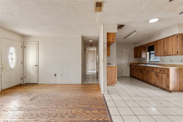 kitchen with a textured ceiling, ceiling fan, light tile patterned floors, and sink