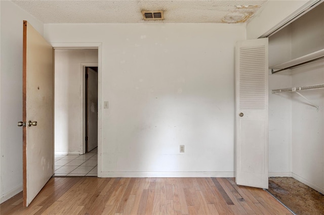 unfurnished bedroom featuring a closet, a textured ceiling, and light hardwood / wood-style floors