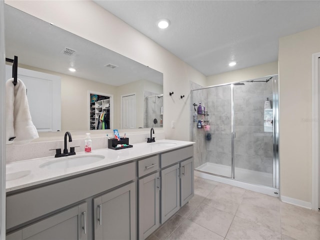 bathroom with tile patterned flooring, a shower with door, and vanity