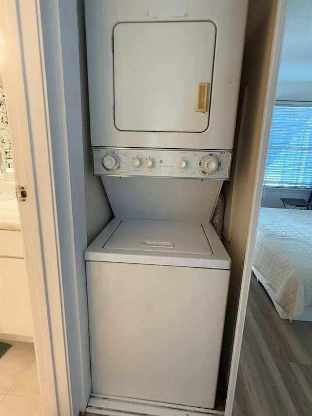 clothes washing area with light tile patterned floors and stacked washer and dryer