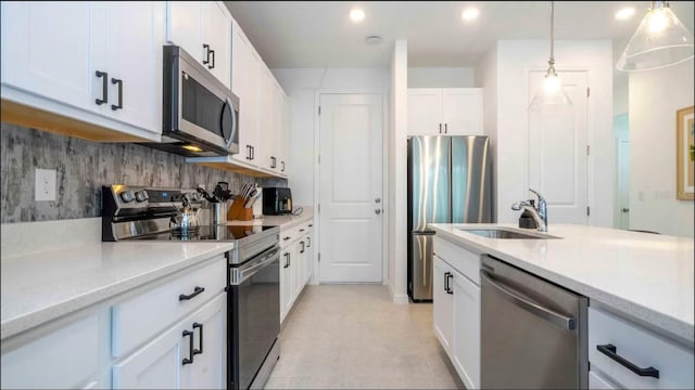 kitchen featuring appliances with stainless steel finishes, tasteful backsplash, hanging light fixtures, white cabinets, and sink