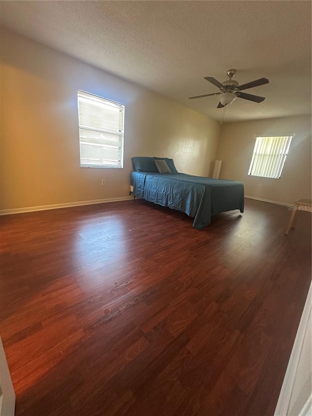 unfurnished bedroom with ceiling fan, dark wood-type flooring, and a textured ceiling