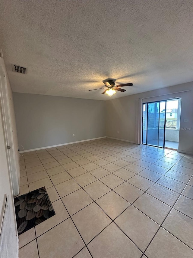 spare room with a textured ceiling, ceiling fan, and light tile patterned floors