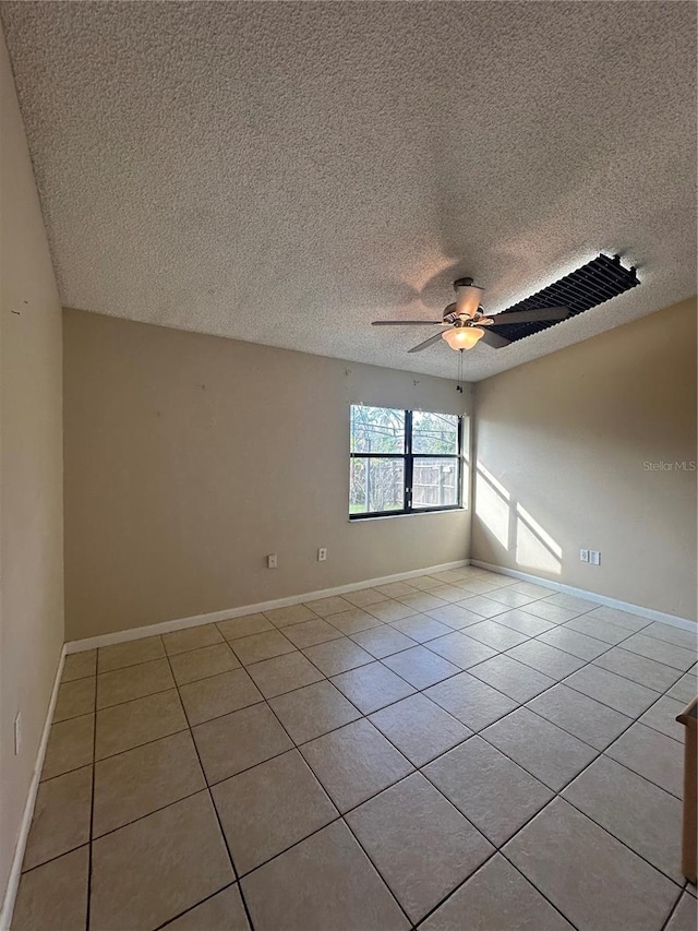 tiled empty room with ceiling fan and a textured ceiling