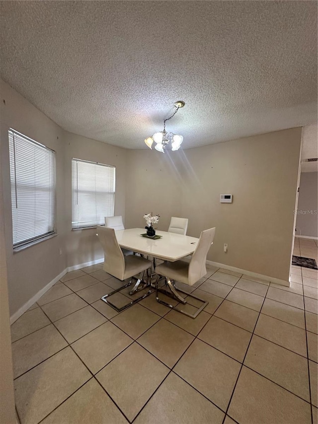 unfurnished dining area featuring a textured ceiling, a notable chandelier, and light tile patterned flooring