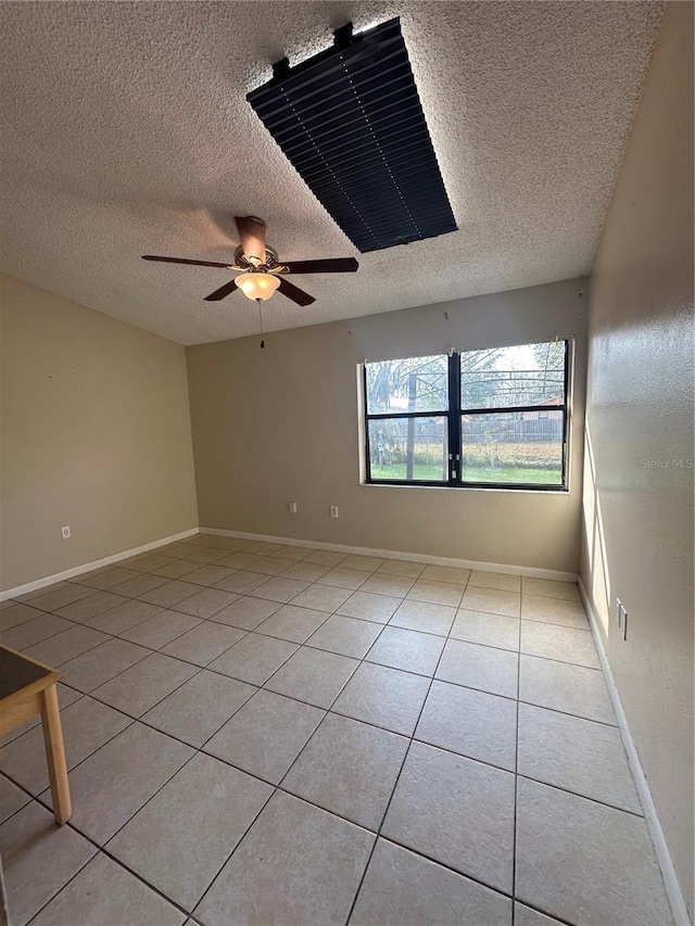 empty room featuring ceiling fan, light tile patterned floors, and a textured ceiling