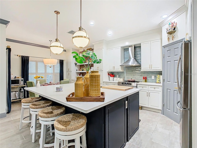 kitchen with white cabinetry, wall chimney range hood, a center island, and appliances with stainless steel finishes