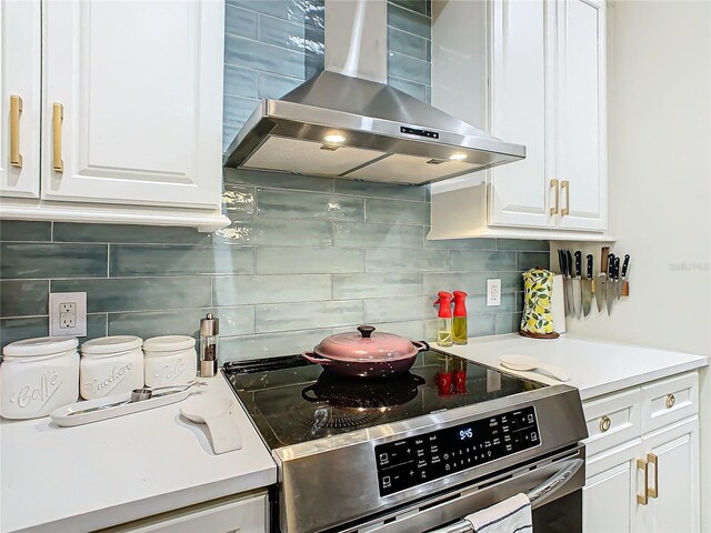 kitchen with tasteful backsplash, range hood, white cabinets, and stainless steel electric range oven