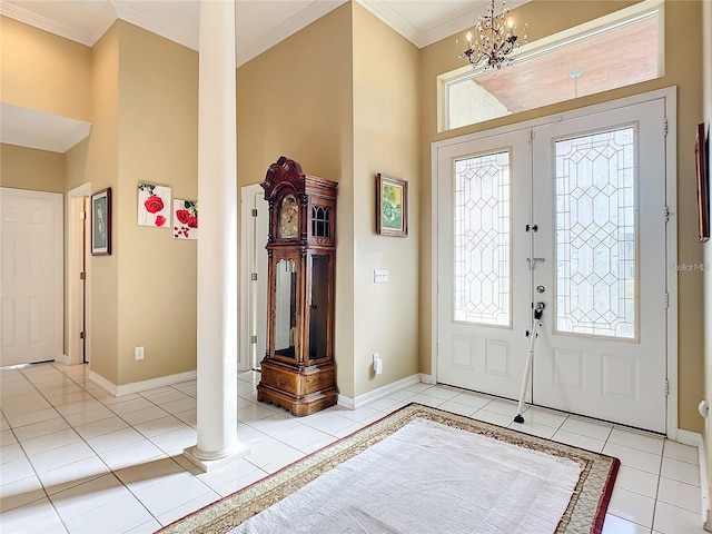 foyer entrance with french doors, light tile patterned floors, ornamental molding, decorative columns, and an inviting chandelier