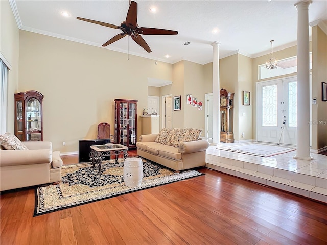 living room with decorative columns, ornamental molding, and ceiling fan with notable chandelier