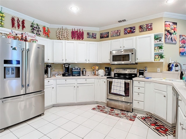 kitchen with stainless steel appliances, white cabinetry, ornamental molding, and light tile patterned flooring