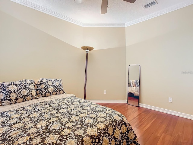 bedroom with ceiling fan, hardwood / wood-style floors, ornamental molding, and a textured ceiling