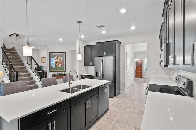 kitchen featuring an island with sink, appliances with stainless steel finishes, sink, and pendant lighting