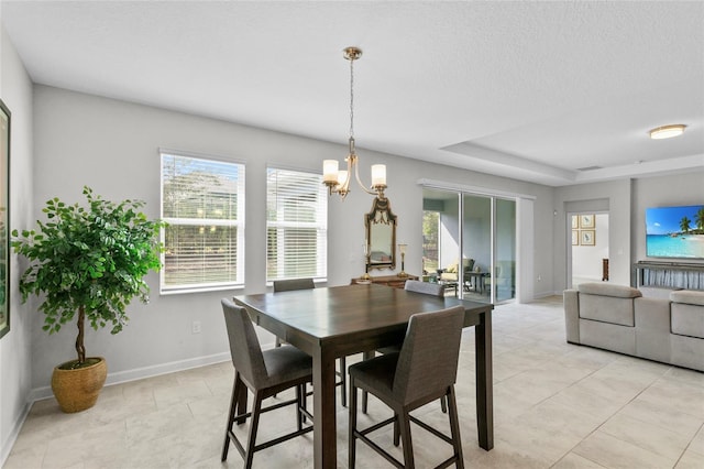 dining area with a raised ceiling and a chandelier