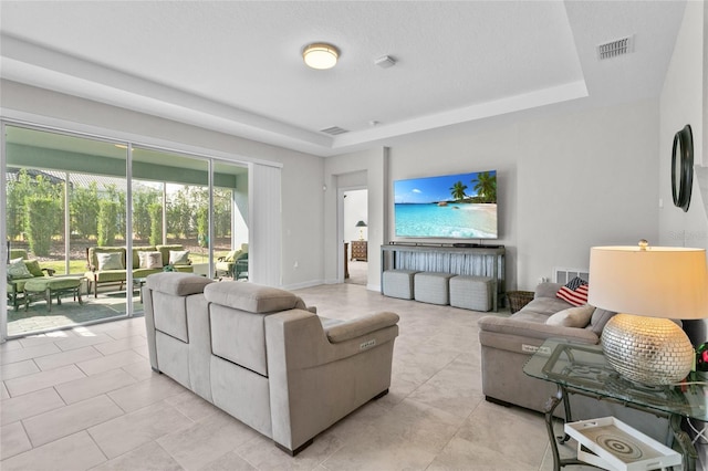 living room featuring a tray ceiling and light tile patterned flooring