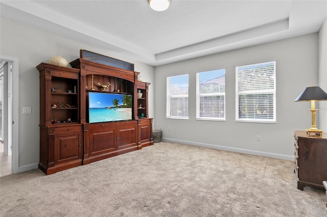 living room with light carpet, plenty of natural light, and a raised ceiling